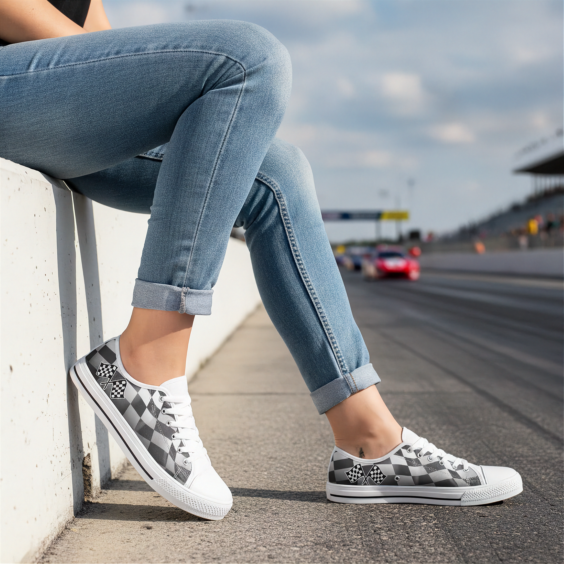 Woman wearing checkered shoes sitting on a curb with a race track in the background