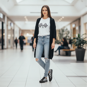 Woman wearing a white t-shirt with a graphic design and checkered shoes, black cardigan, and ripped jeans in a mall setting.