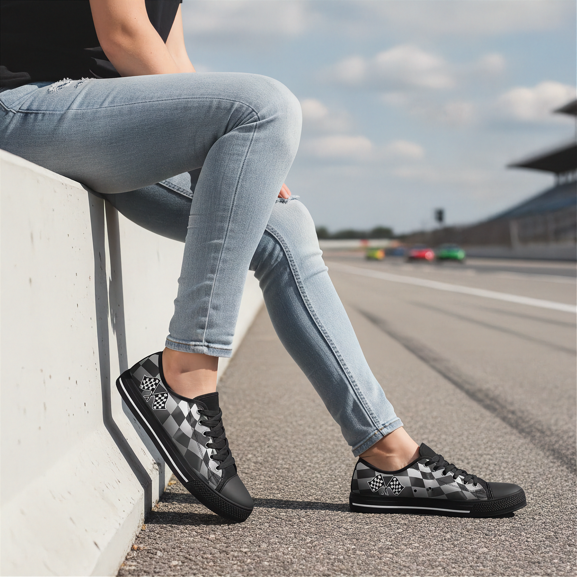 Person wearing black checkered shoes on a race track with cars in the background