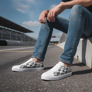 Person wearing checkered sneakers and blue jeans sitting on a concrete barrier with a road and sky in the background.