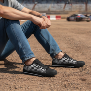 Person wearing black and gray checkered sneakers on a dirt track.