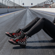 Person wearing checkered racing boots on a racetrack