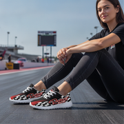 Woman sitting on a race track wearing checkered sneakers with 'Racing Mom' text.