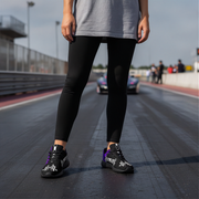 Woman wearing black leggings and racing girl shoes on a racetrack