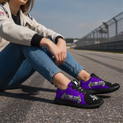 Woman sitting on a race track wearing purple and black sneakers with 'Racing Gear' text.