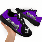 Purple and black sneakers with 'Racing Girl' text held by a hand on a white background