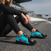 Woman wearing black and blue sneakers with 'Racing Girl' design on a racetrack.