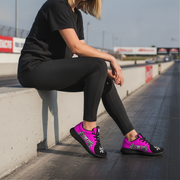 Woman sitting on a drag race track wearing black and pink racing girl sneakers
