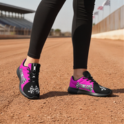 Woman wearing black and pink athletic shoes on a dirt track