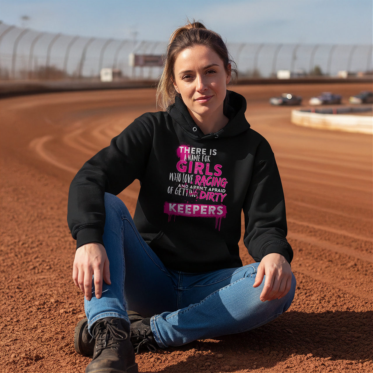 Woman sitting on a race track wearing a hoodie with text.