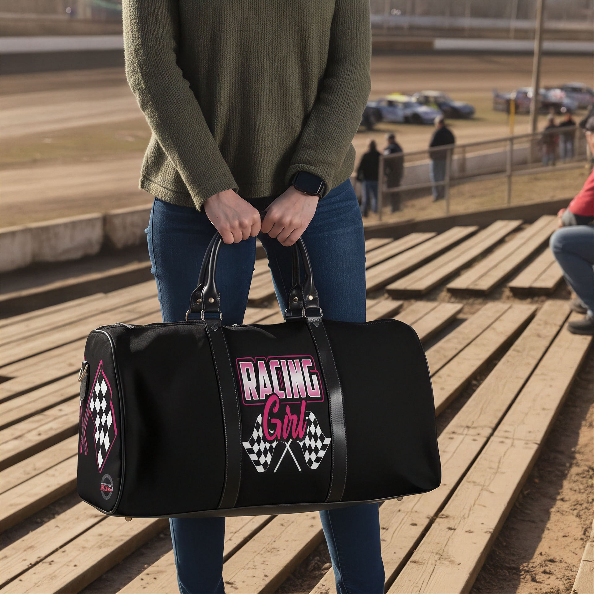 Woman holding a black duffel bag with 'Racing Girl' text at a race track.