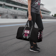 Woman holding a black duffel bag with 'Racing Girl' text on a race track.