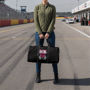 Woman holding a black duffel bag with 'Racing Girl' text on a race track.