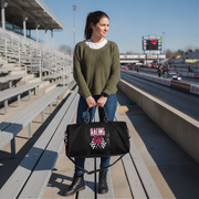 Woman holding a black duffel bag with 'Racing Girl' text at a race track.