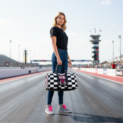 Woman holding a travel bag with a pink racing girl and checkered flag design at a dragstrip, customizable text.