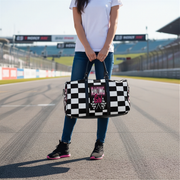 Woman holding a travel bag with a pink racing girl and checkered flag design at a race track, customizable text.