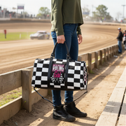 Woman holding a travel bag with a pink racing girl and checkered flag design at a dirt race track, customizable text.
