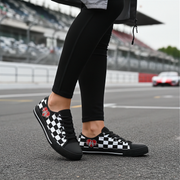 Person wearing black and white checkered low top shoes on a race track.