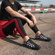 Woman sitting on a race track black and white checkered low top with heart designs on a dirt track.
