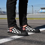 Man wearing a Black checkered low top shoes with red heart designs on a racetrack.