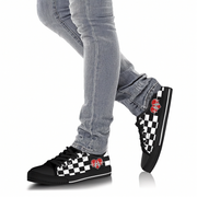 Man wearing black and white checkered low top shoes with heart designs on a white background