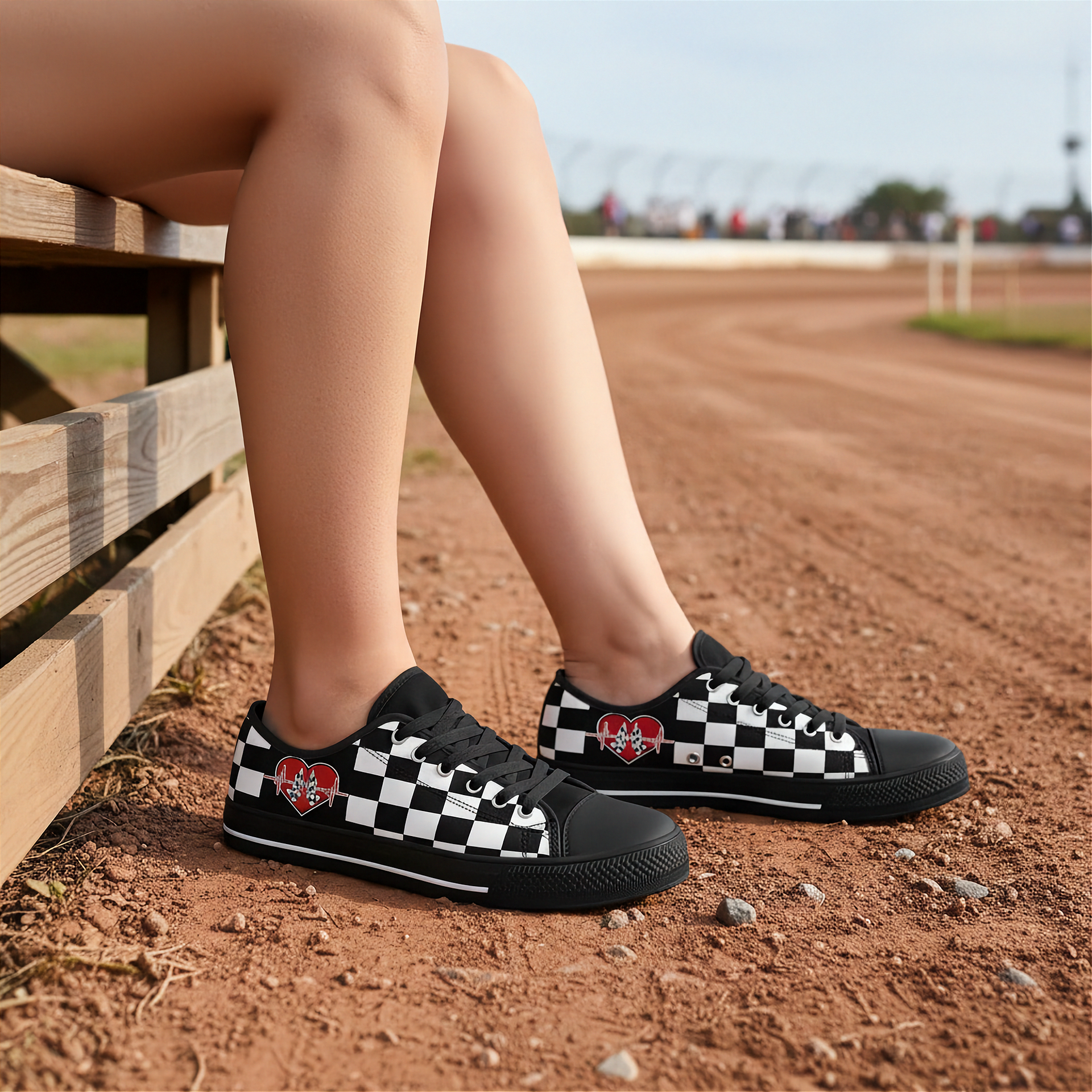 Woman wearing black and white checkered low top with heart designs on a dirt track.