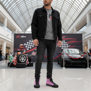 Man wearing checkered high top shoes standing in a modern indoor setting with a car display in the background
