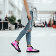Person wearing pink and black checkered high-top shoes in a blurred indoor setting