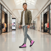Man walking in a mall wearing a green bomber jacket, white shirt, ripped jeans, and checkered shoes.