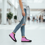 Person wearing pink checkered high-top shoes in a blurred indoor setting