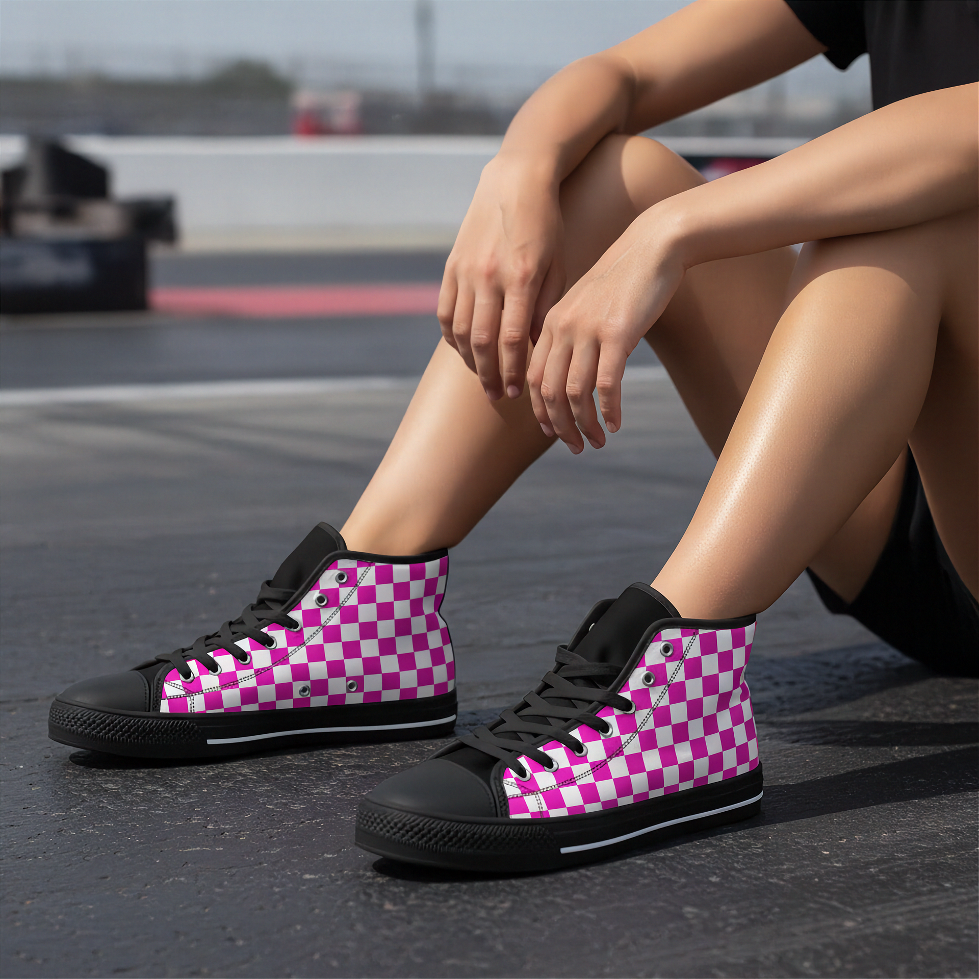 Person wearing pink and black checkered high-top shoes on a racetrack.