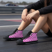 Woman wearing pink and black checkered high-top sneakers on a road.
