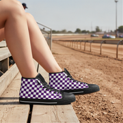 Person wearing purple and black checkered sneakers on a wooden platform with a race track background.