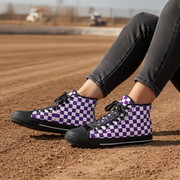 Person wearing purple and white checkered high-top shoes on a dirt surface.