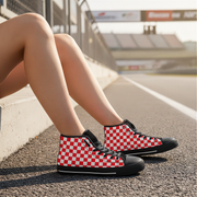 Red and black checkered high-top sneakers on a person's feet by a road.