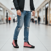 Person wearing ripped jeans and checkered shoes in a blurred indoor setting