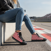 Person sitting on a race track wearing red and white checkered shoes.