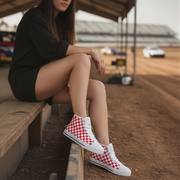 Person wearing red and white checkered shoes sitting on a wooden bench.