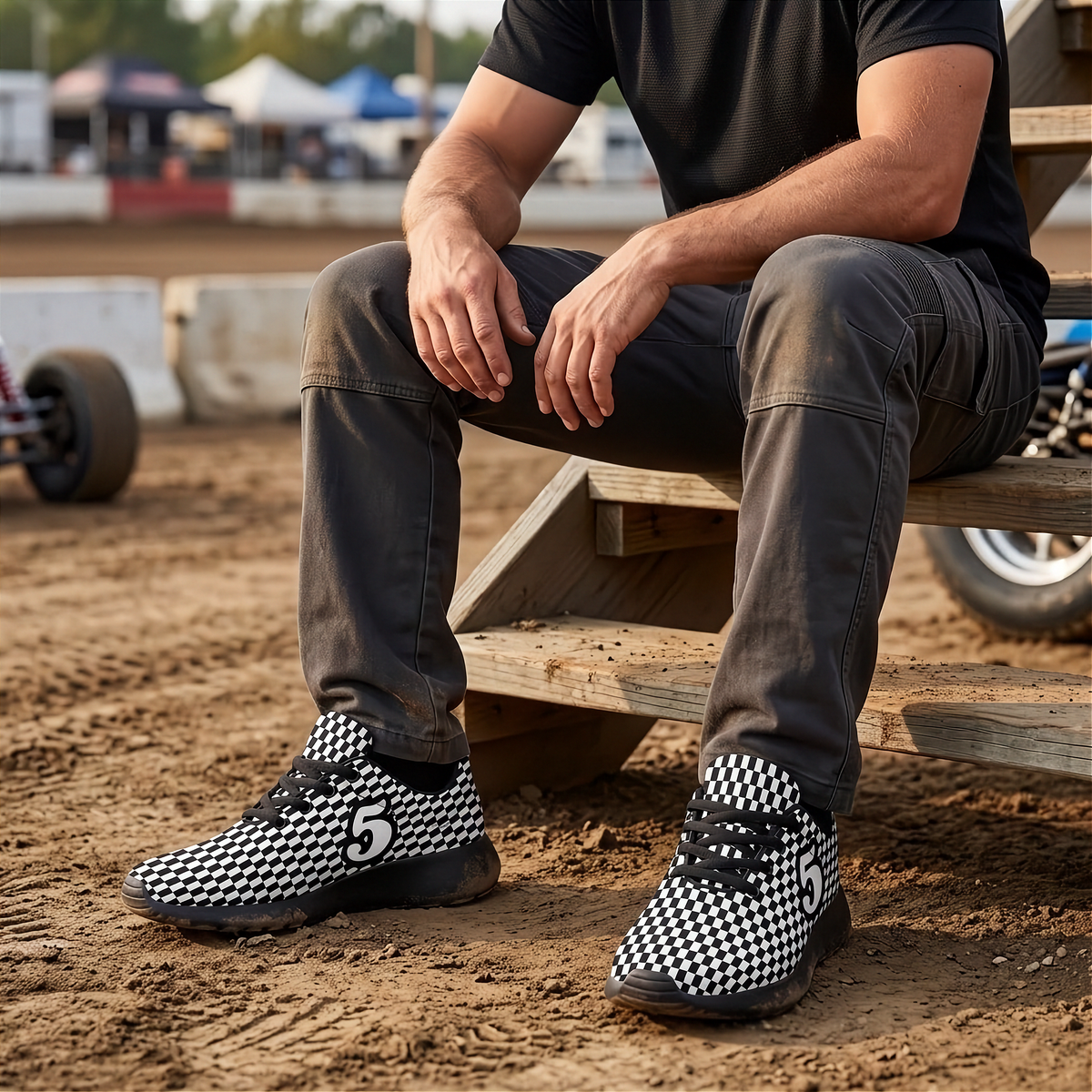 A man sitting on a wooden bleacher at a dirt track wearing black and white checkered sneakers with the number 5 on the side.