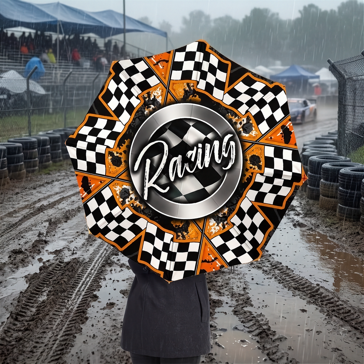 A person holding a large racing-themed umbrella in a muddy, rainy racetrack setting. The umbrella features a black and white checkered pattern, orange accents, and a central silver ring with the word 'Racing' in white script.