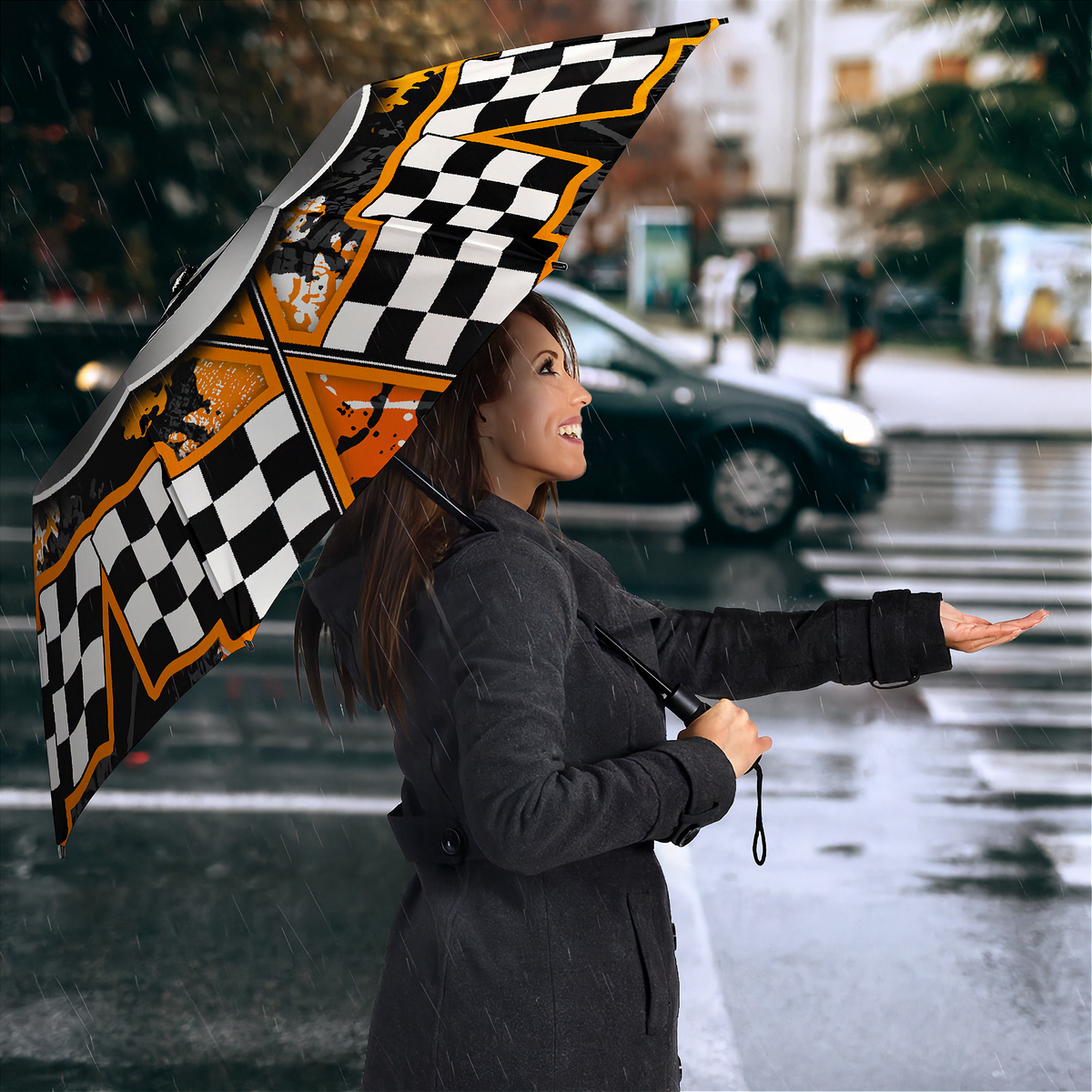A woman in a dark gray coat stands in the rain holding an open umbrella with a black and white checkered pattern and orange accents. A blurred car and city street are visible in the background.