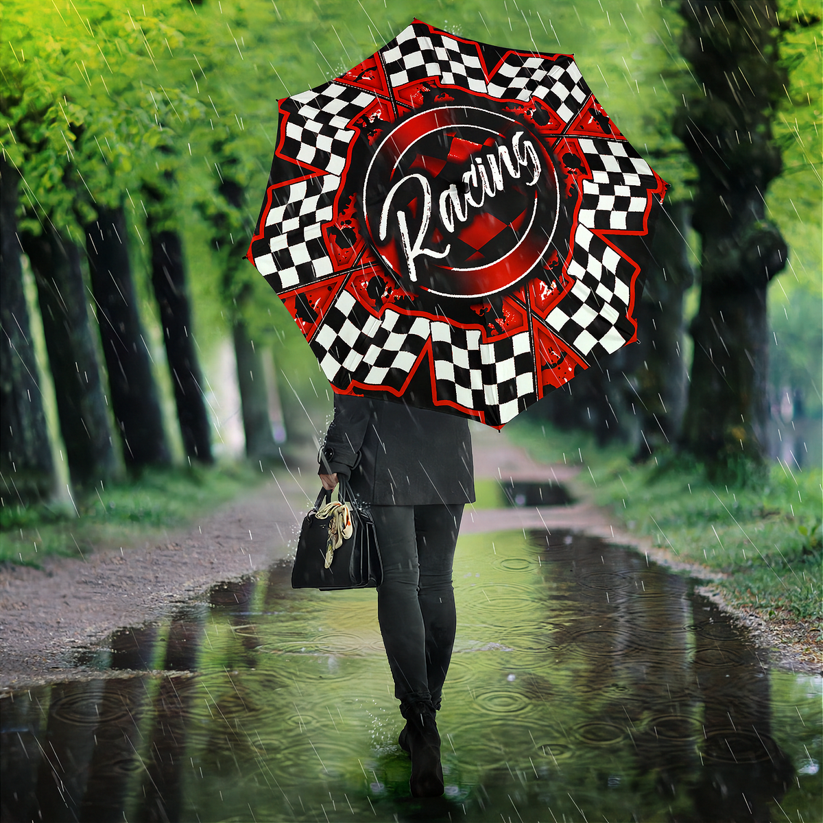 A person walking in the rain holding a large racing-themed umbrella. The umbrella features a red and black center with the word 'Racing' in white script, surrounded by red and black checkered segments.
