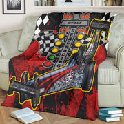 Red-and-black dragster blanket spread across a cream sofa, displaying the car photo and drag racing starting lights.