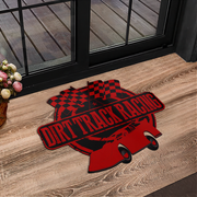 A red and black 'Dirt Track Racing' graphic mat placed on a wooden floor in front of a glass door.