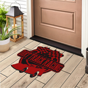 A red and black 'Drift Track Racing' doormat featuring a race car and checkered flag design, shown on a light wood porch floor in front of a tan front door.