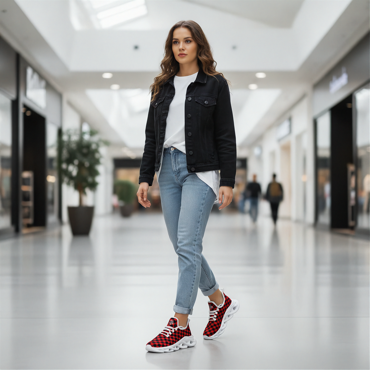 Woman walking in a modern mall wearing a black jacket, white shirt, light blue jeans, and red checkered sneakers.