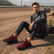 Man sitting on a dirt track wearing red and black checkered shoes