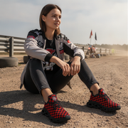 Woman sitting on a dirt track wearing red and black checkered shoes.