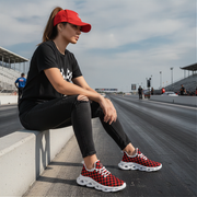 Person wearing red and black checkered sneakers sitting on a track.