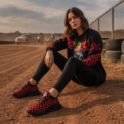 Woman sitting on a dirt track wearing red and black checkered shoes and outfit.